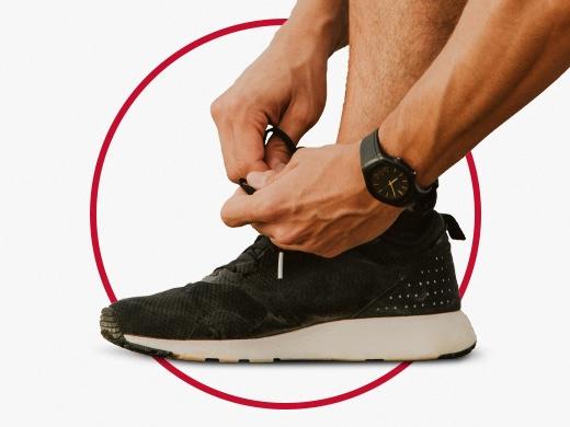 Sporty man with black watch tying shoelace