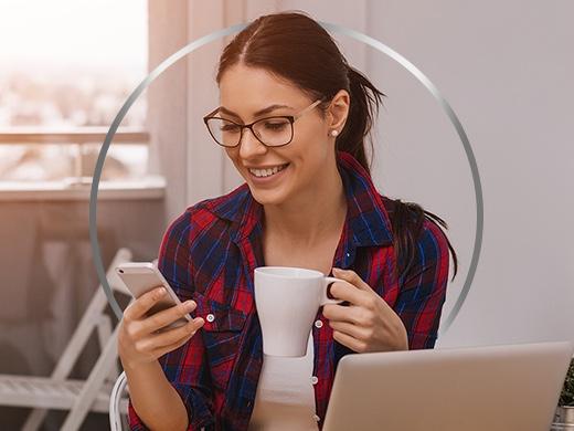 Smiling young woman wearing glasses on her phone happy after Canesten thrush treatment